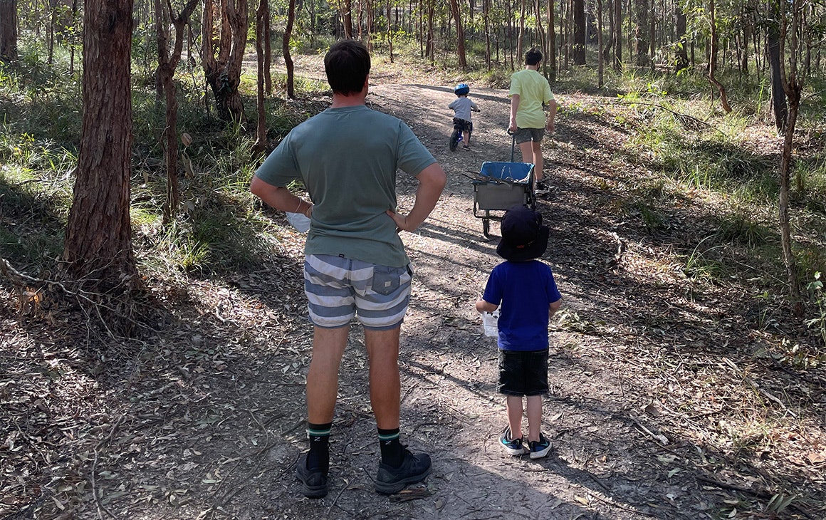 a dad and three kids walking through bushland